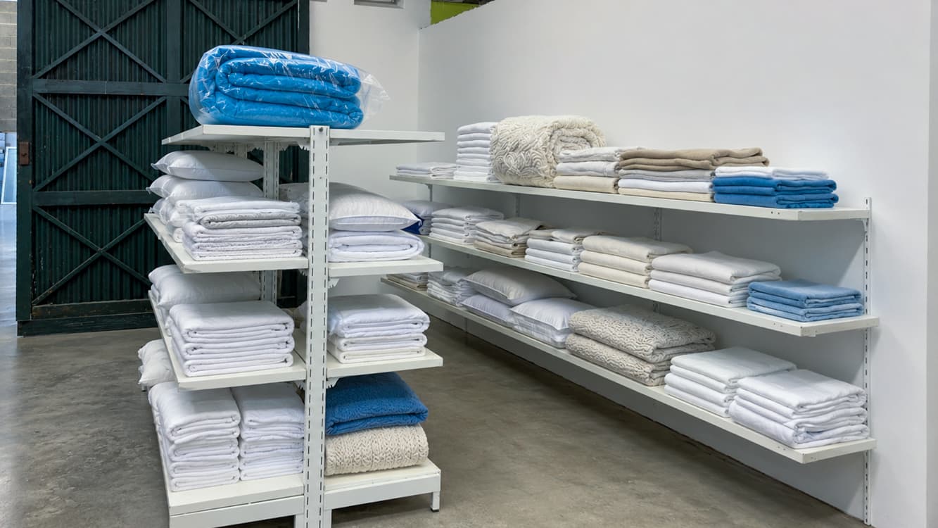 Shelves of folded sheets, towels and pillows, sorted and ready to go back out.
