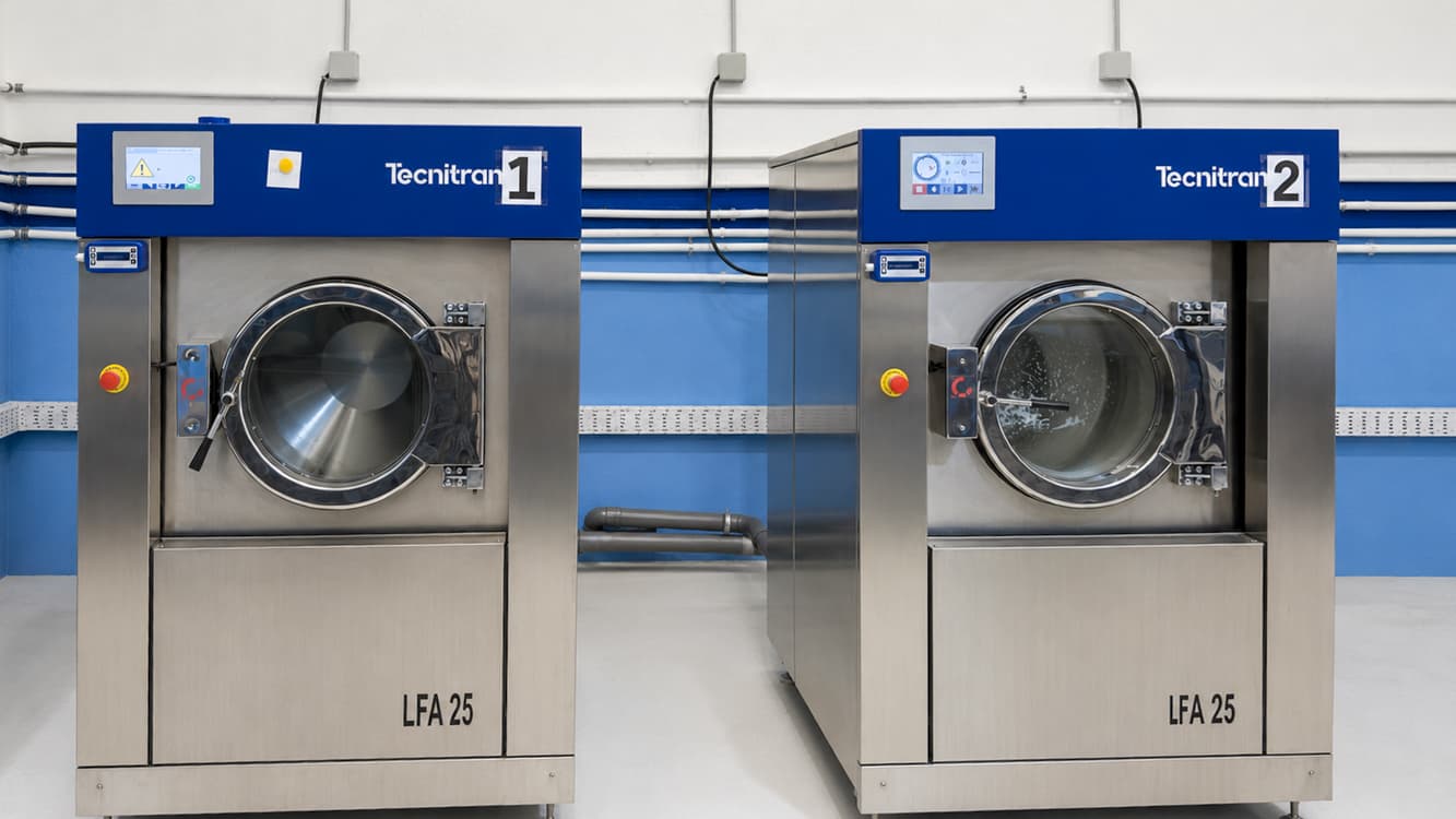 Two Tecnitran industrial washing machines at the Loulé plant, against the blue wall of the floor.